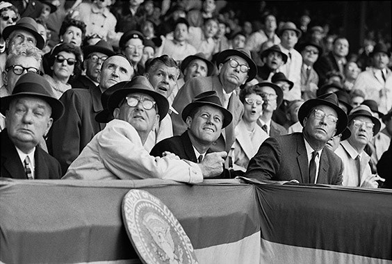 Griffith Stadium, Washington, DC, April 10, 1961

I was eighteen years old and the idea of sitting twenty feet in front of the President was more thrilling than shooting any baseball game could ever be. Unfortunately, by the third or fourth inning, it was clear that I hadn’t yet gotten any memorable pictures. I’d hoped that Kennedy would do something to make a good picture. He might eat a hot dog and end up with a little mustard on his lip. Johnson ate one, but he wasn’t the subject I was there to shoot. Kennedy didn’t order a dog, but he donned a fedora – which was not a bad picture. Finally, I got lucky when a foul ball came dangerously close to the presidential box, causing the President, Vice President, and Democratic and Republican leaders from both houses of Congress to all lean to the left. Surely it was the most bipartisan moment of 1961.