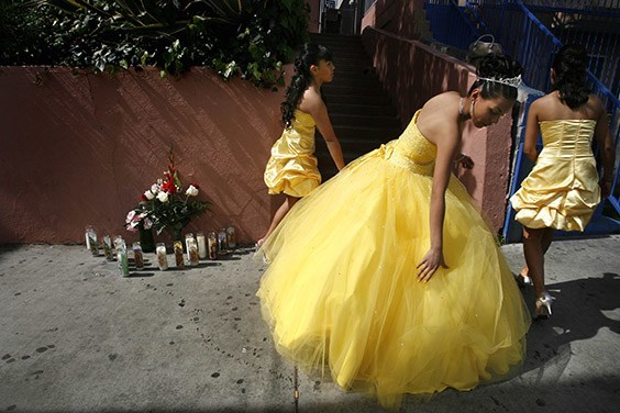 Jessica Alvarado fixes her Quinceañera dress on a blood-stained sidewalk next to a memorial honoring tamale vendor Cosme Gonzaleza, who was robbed and killed in front of her Los Angeles home.