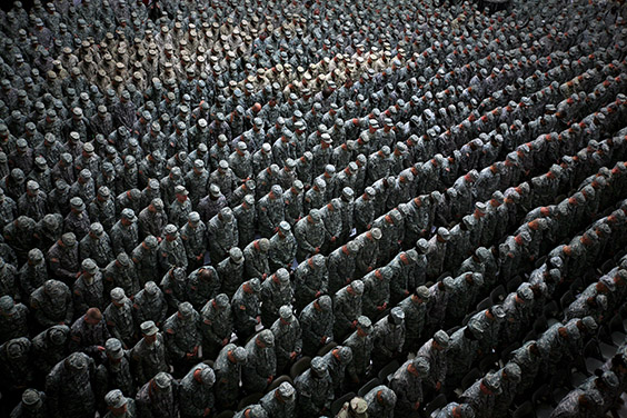 1,215 American soldiers, airmen, marines (patch of lighter uniforms in top left corner) and seamen (patch of lighter uniforms in top center) pray before the pledge of enlistment on July 4, 2008, at a massive re-enlistment ceremony in Al Faw palace in Baghdad, Iraq on July 4, 2008. (Photo by Ashley Gilbertson / VII Network)