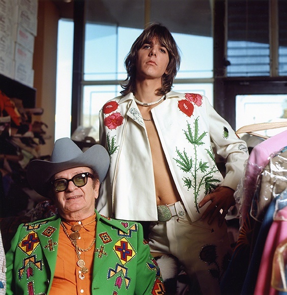 Gram Parsons (standing), adopting the rhinestone look of his country music heroes, in a personalized suit designed by Nashville’s favorite tailor, Nudie Cohn (seated), at Nudie’s Rodeo Tailors shop, Los Angeles, 1968