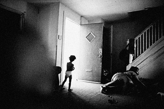 From “A [neighbor]Hood Story”: Young girl in doorway of her uncle’s three-bedroom home, which then contained 12 family members who were financially dependent on each other, in the notoriously dangerous Sun Village neighborhood in Chester, Pennsylvania.