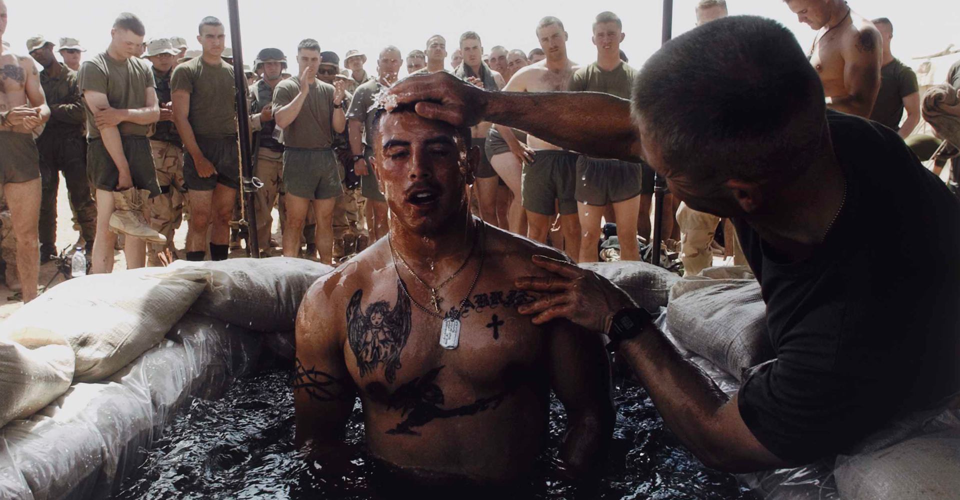 Navy Chaplain Lt. Commander Tom Webber baptizes Corporal Albert Martinez in a sandbag-lined pool during a ceremony at Camp Inchon, Kuwait - March 2003
