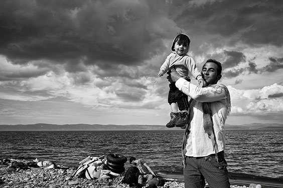 A father celebrates his family's safe passage to Lesbos after a stormy crossing over the Aegean Sea from Turkey.